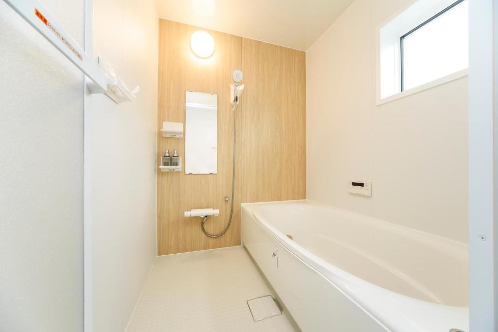 Full-length bathtub with wood-panel accent wall and shower